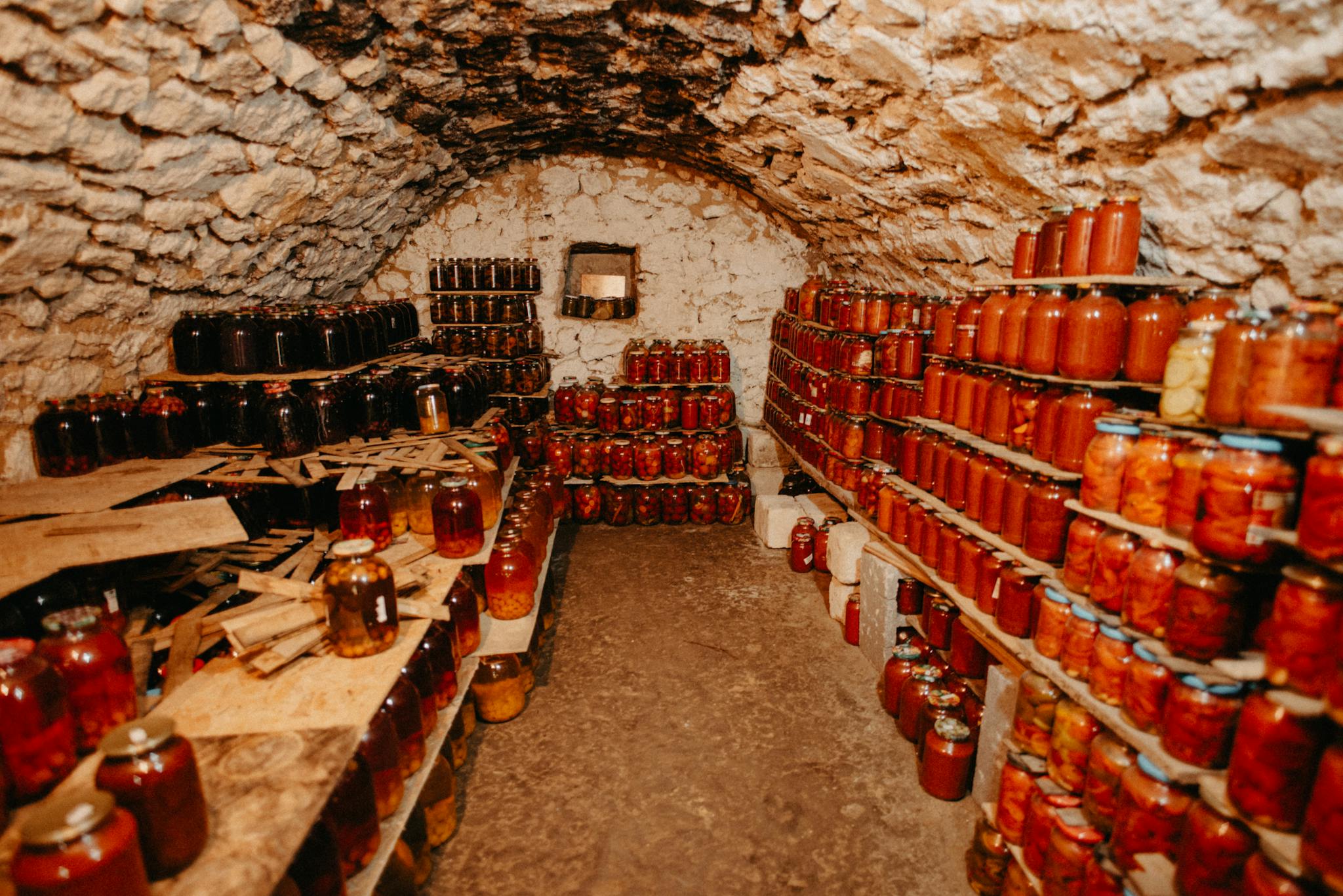 A cozy stone cellar filled with neatly arranged jars of preserves.