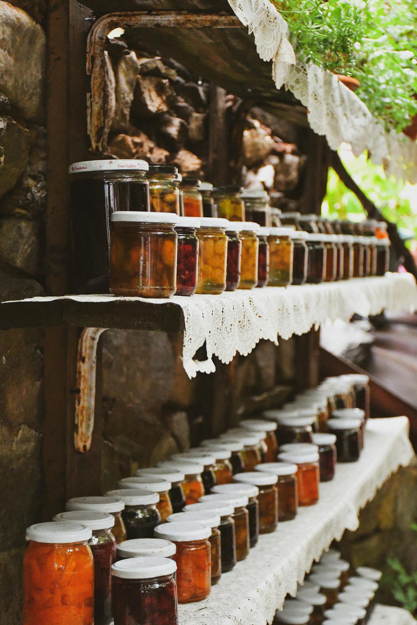 Explore a charming collection of homemade preserves on rustic shelves in an outdoor setting.